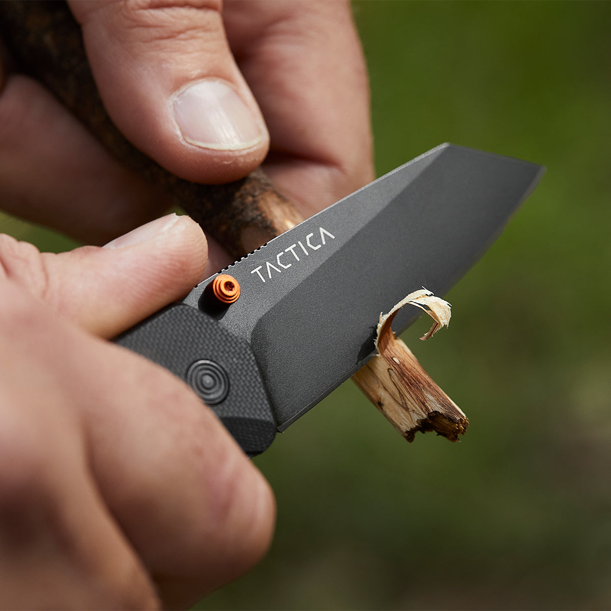 K100 folding pocket knife whittling the end of a stick