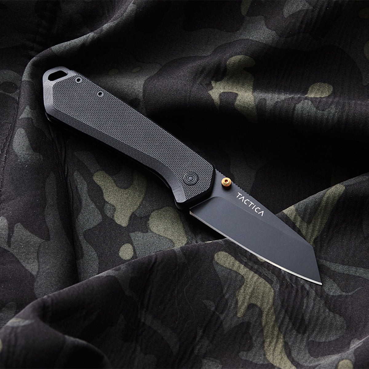 K100 pocket knife laying on a camo background with the blade open