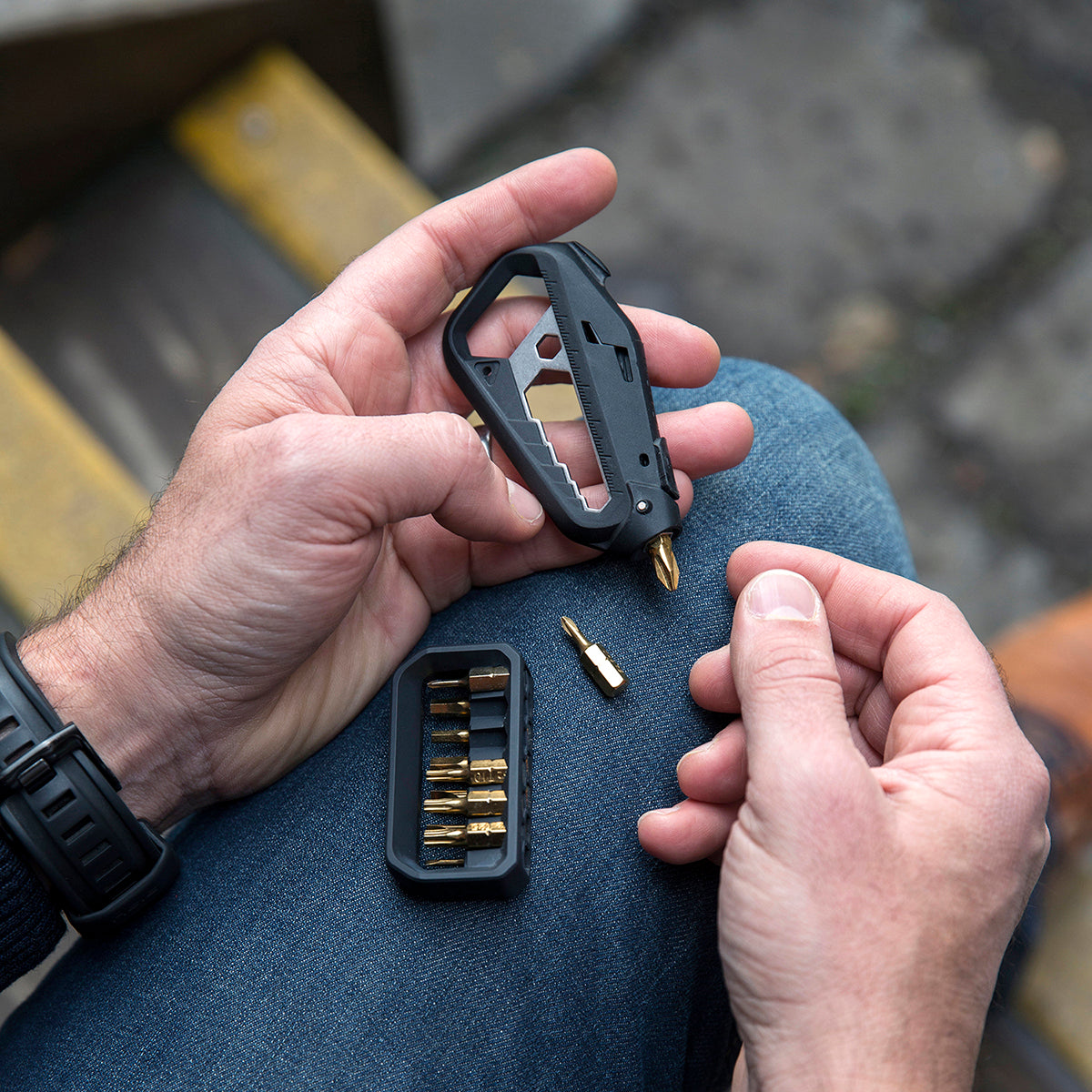 Closeup of a person with the m100 multitool on their leg choosing a screwdriver bit from the holster