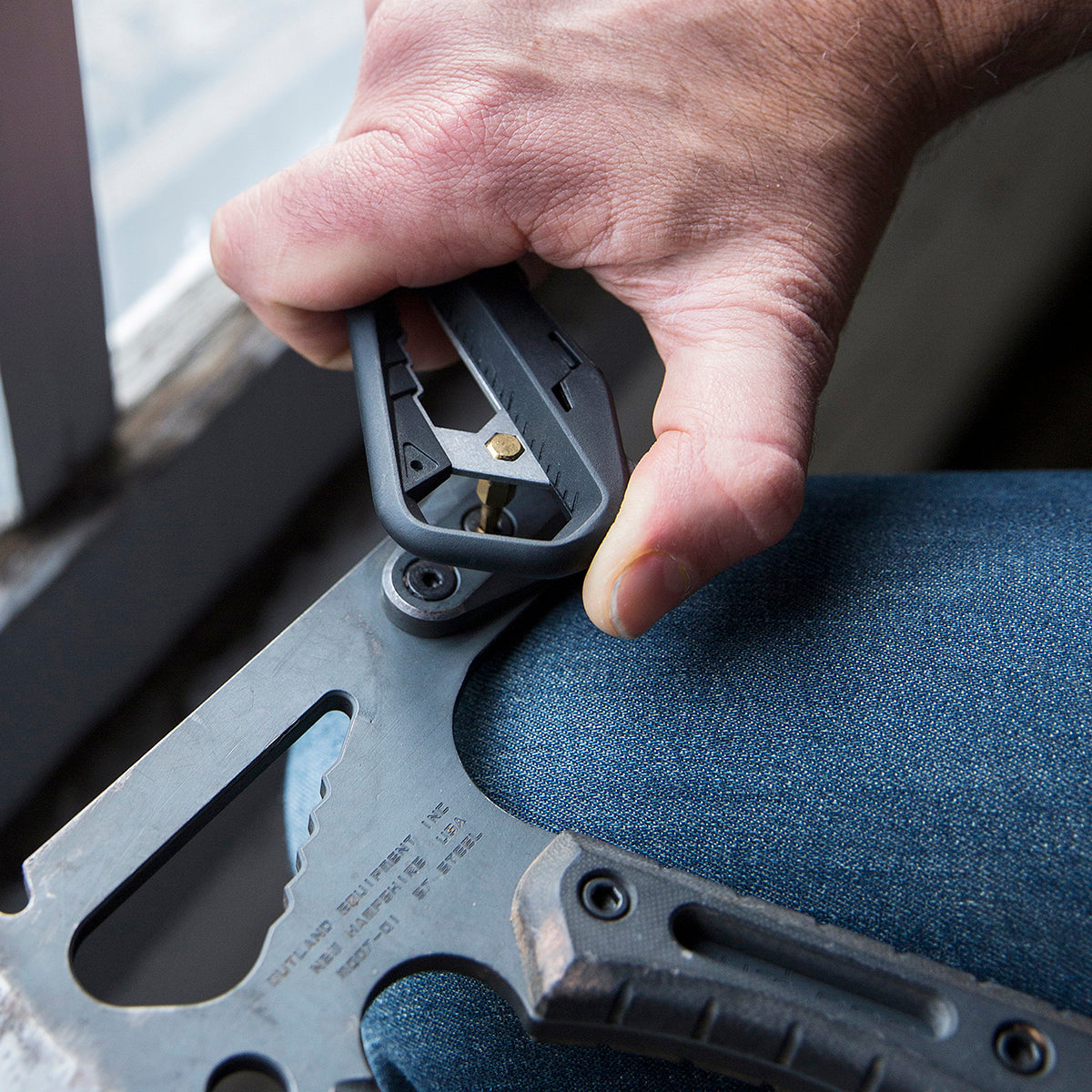 Closeup of person using the m100 multitool to tighten a nut on an outdoor axe