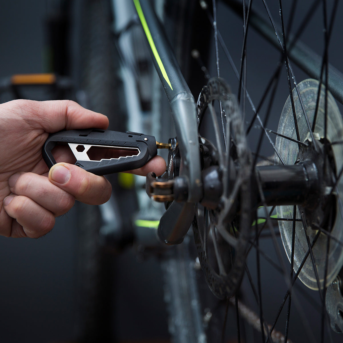 Person using the M110 bike multitool to tighten a screw on the bike