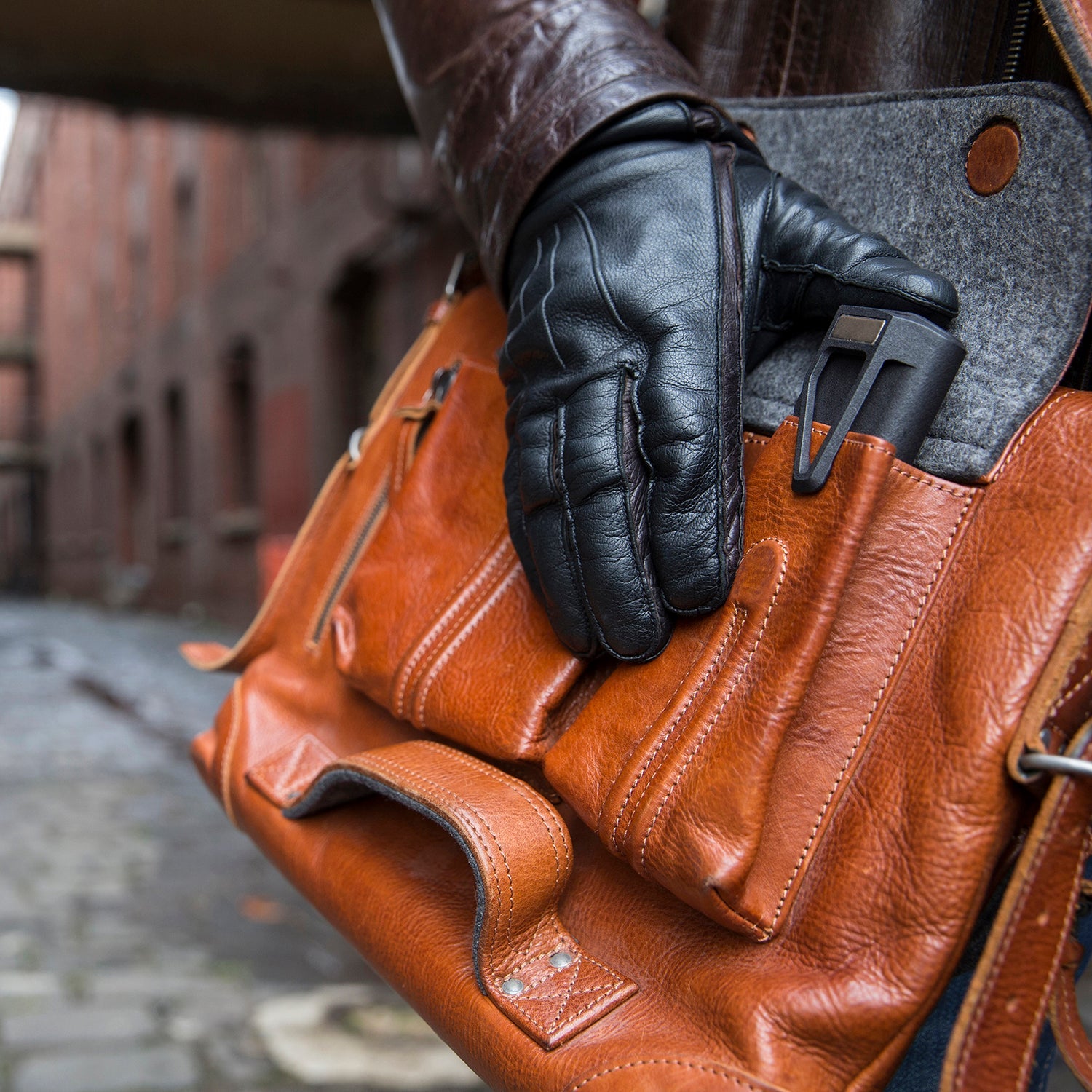 Person sliding the M250 screwdriver toolkit into the outside of a leather bag