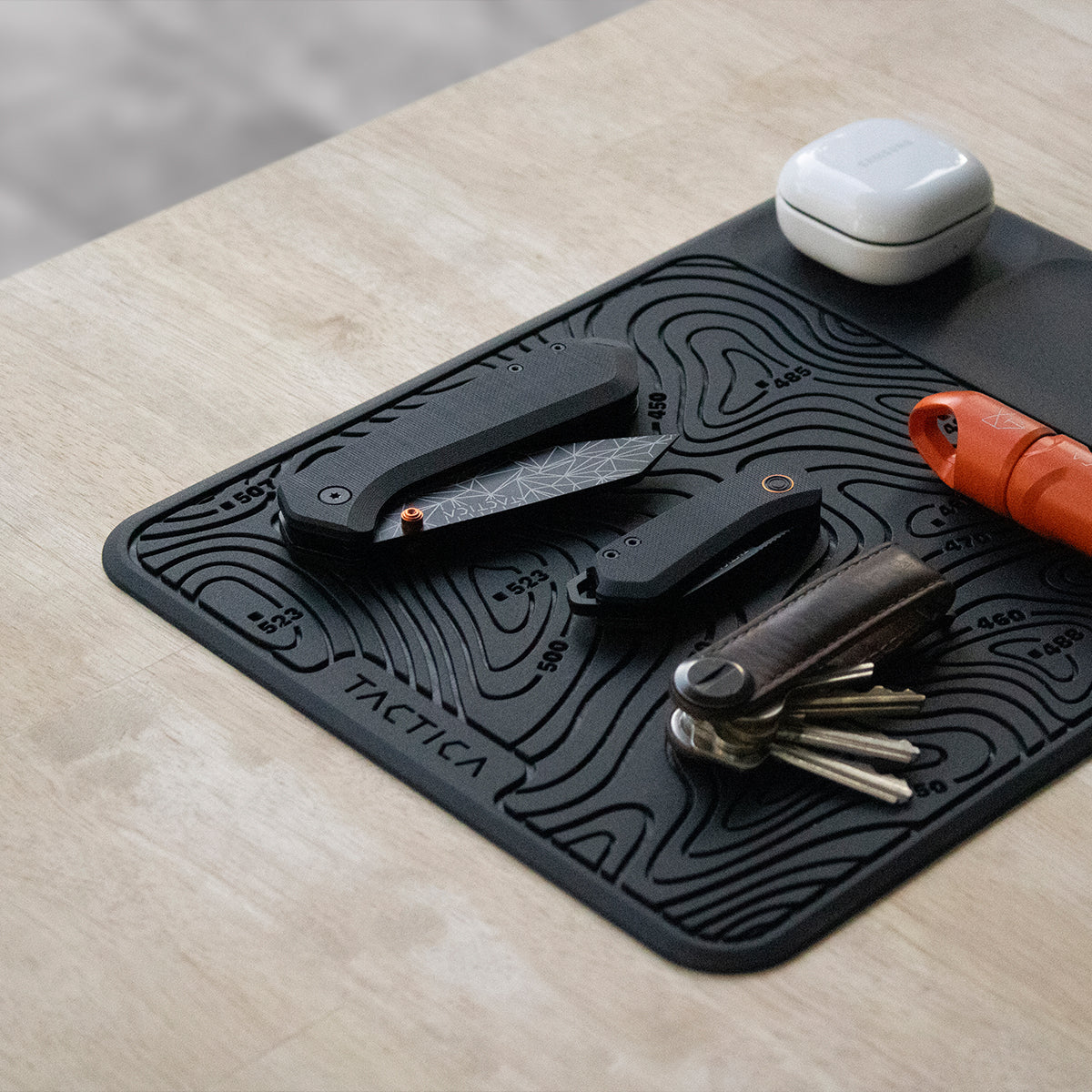 Silicone EDC mat on a wooden table with EDC gear lying on top