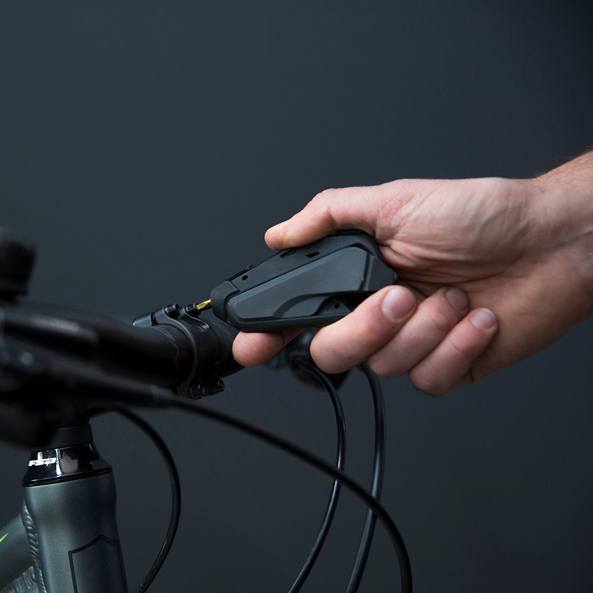 Person using the portable m-110 bike multitool screwdriver to tighten a handlebar